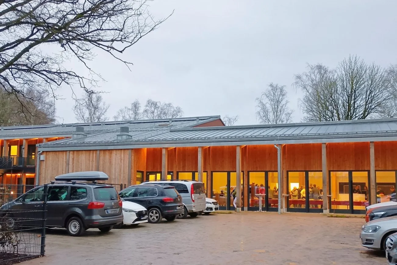 Ein modernes hell erleuchtetes Gebäude an einem Parkplatz.