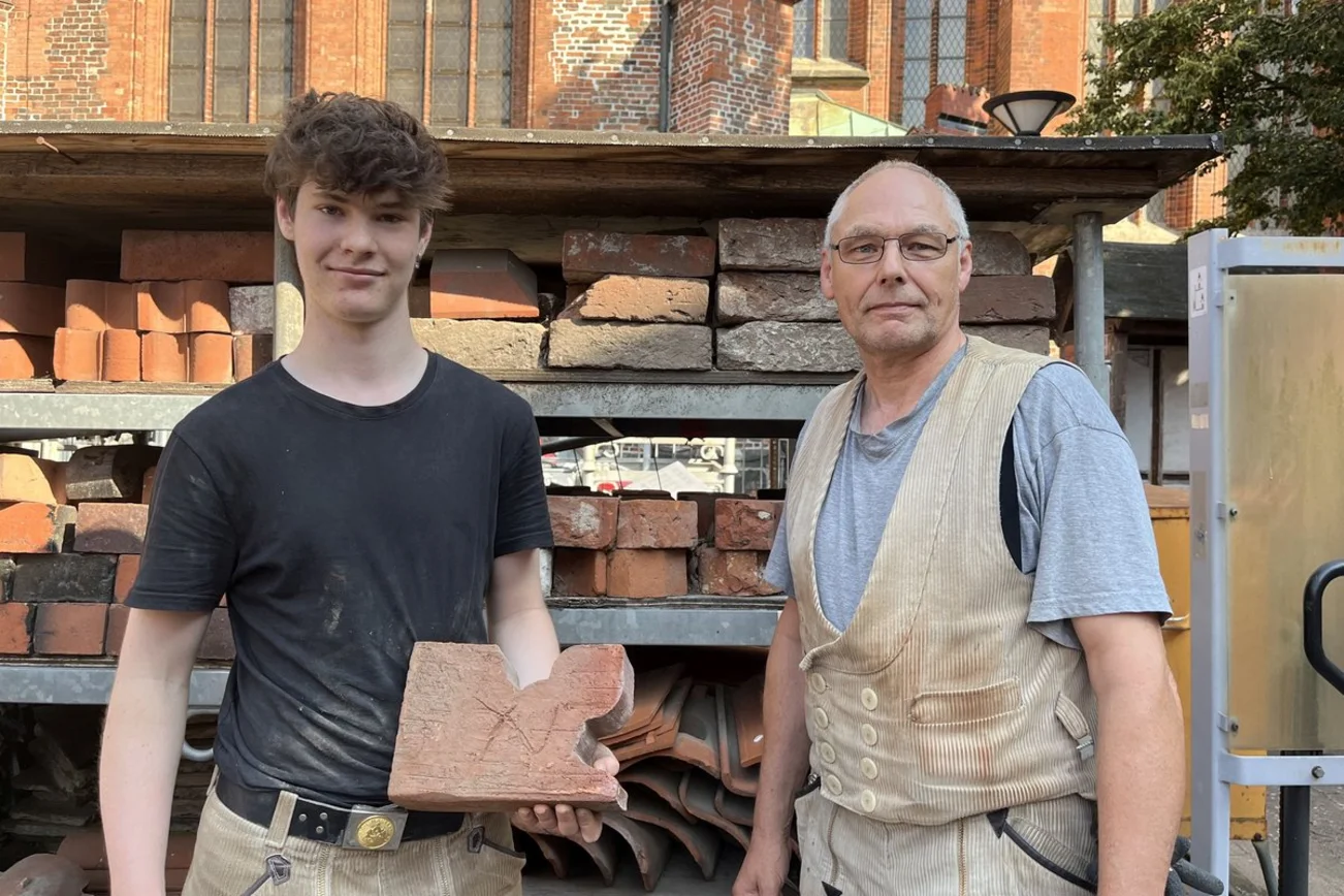 Zwei Männer stehen vor einem Regal mit Ziegelsteinen