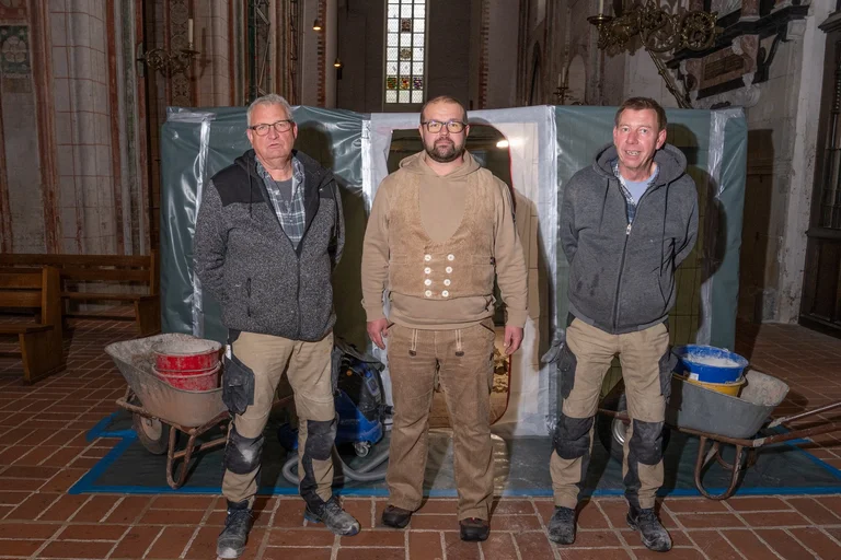 Drei Männer auf einer Baustelle in einer Kirche