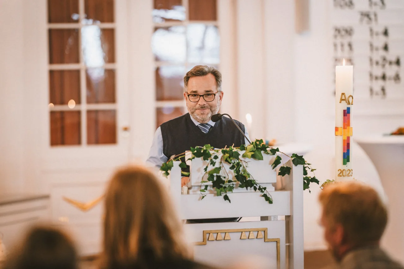 Ein Mann steht am Podium in einer Kirche.