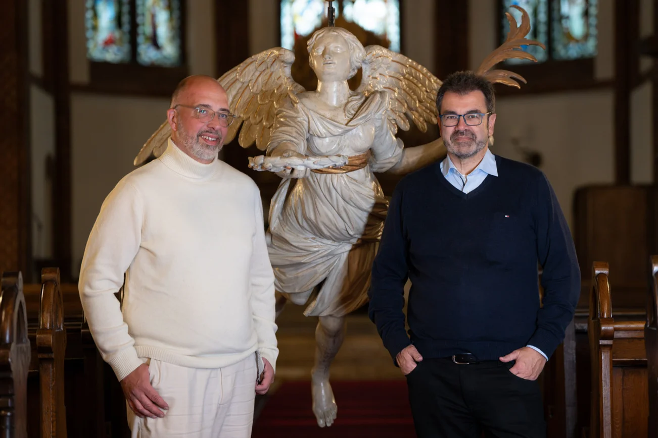 Zwei Männer stehen vor dem Taufengel