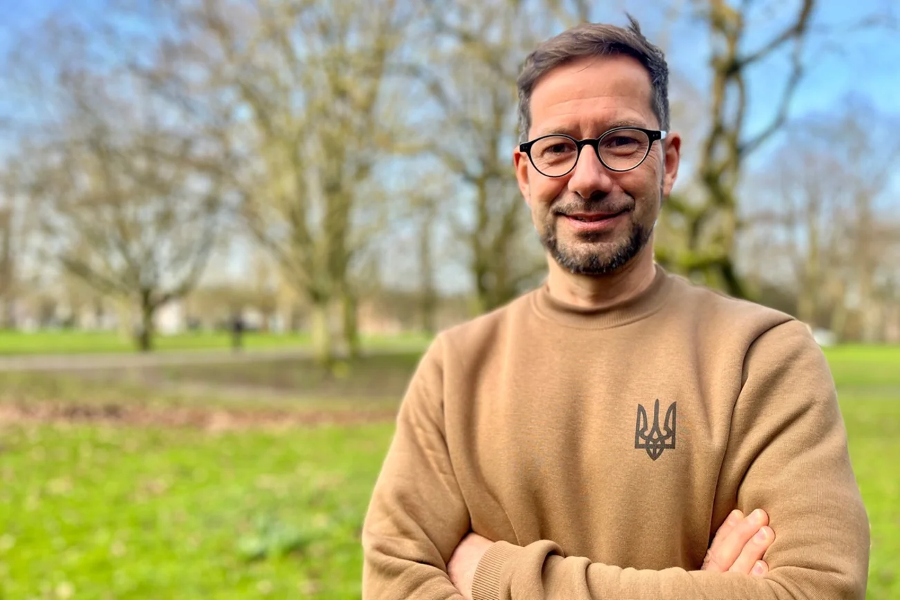 Mann lächelt im Park in die Kamera