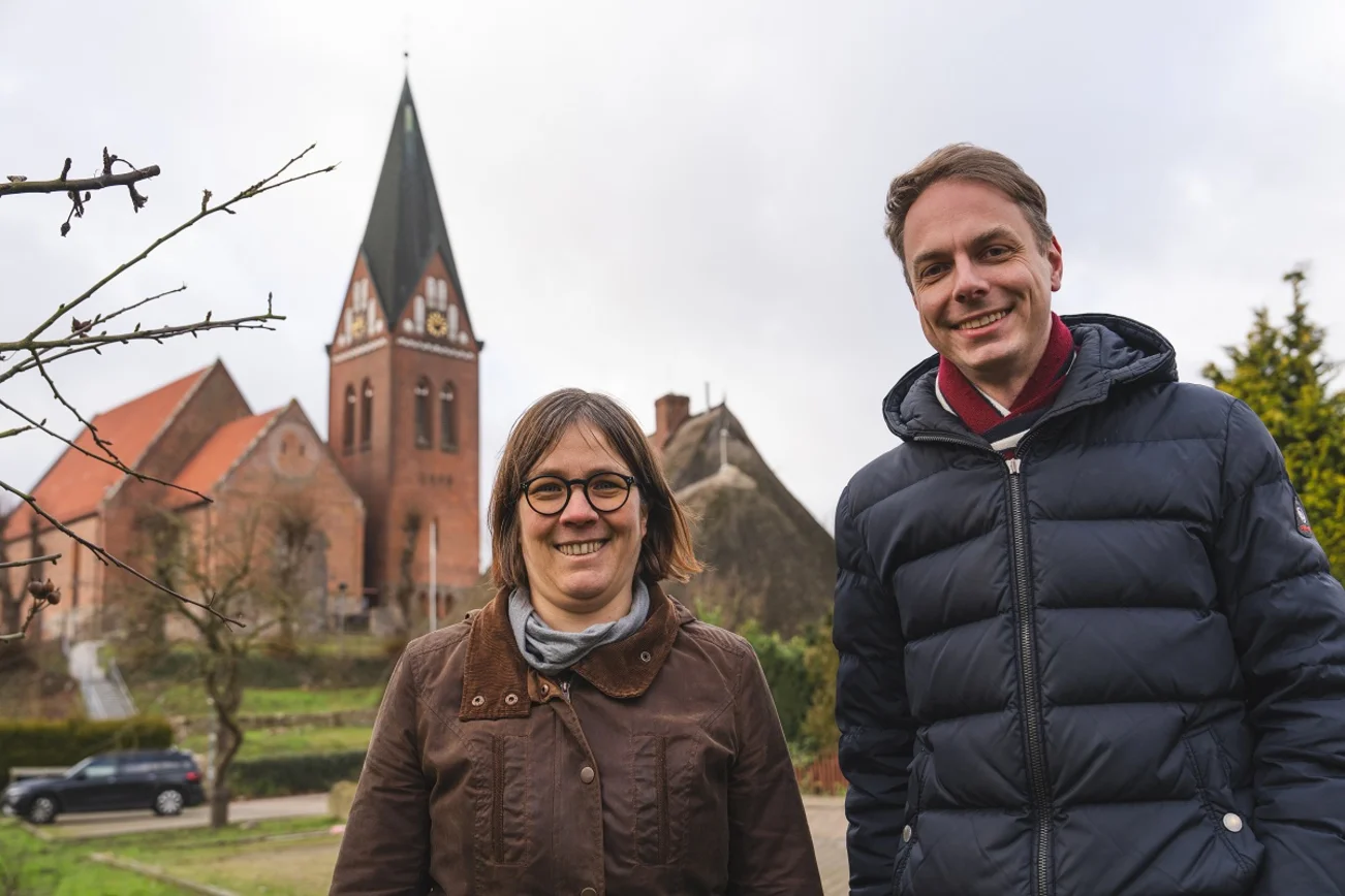 Zwei Personen im Vordergrund, Kirche im Hintergrund