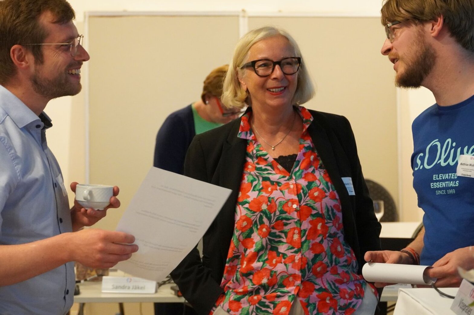 Eine Frau spricht lachend mit zwei Männern.