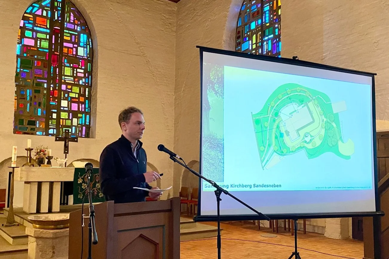 Mann am Mikrofon neben Beamer-Leinwand