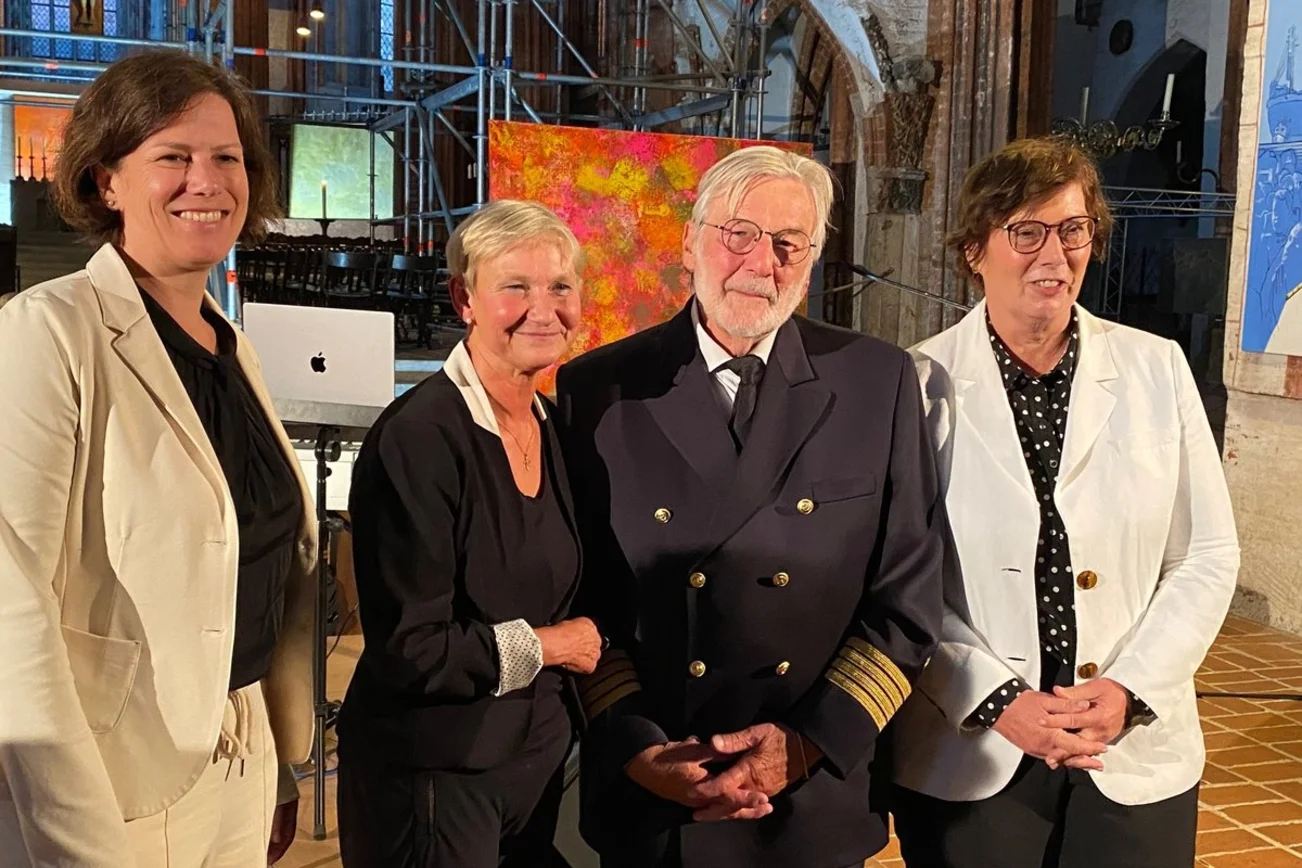 Ein Mann und drei Frauen lächeln für die Kameras