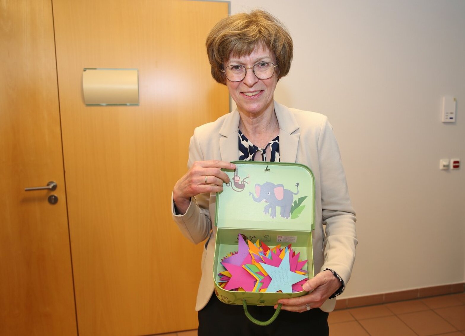 Eine Frau zeigt eine Kiste, in der sich bunte Sterne befinden