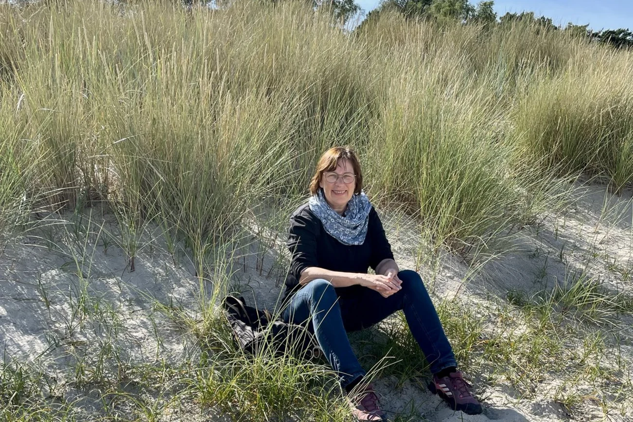 Eine Frau sitzt in einer Düne