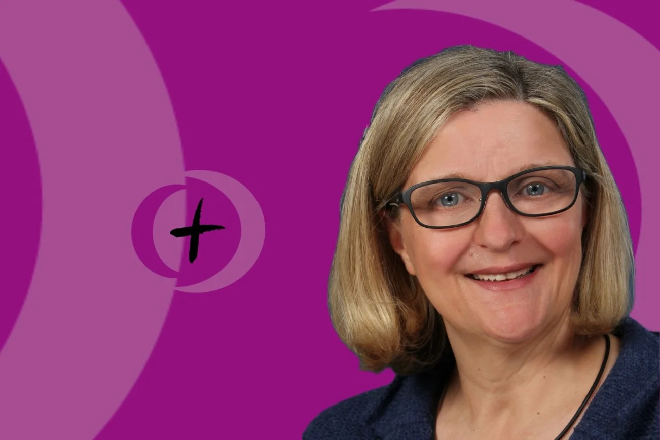 Eine Frau blickt in die Kamera und lächelt.