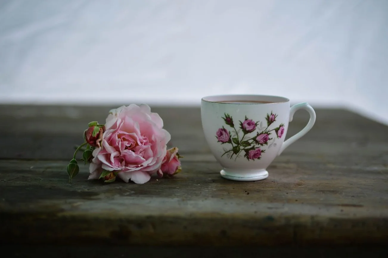 Kaffeetasse, daneben liegt eine Rose