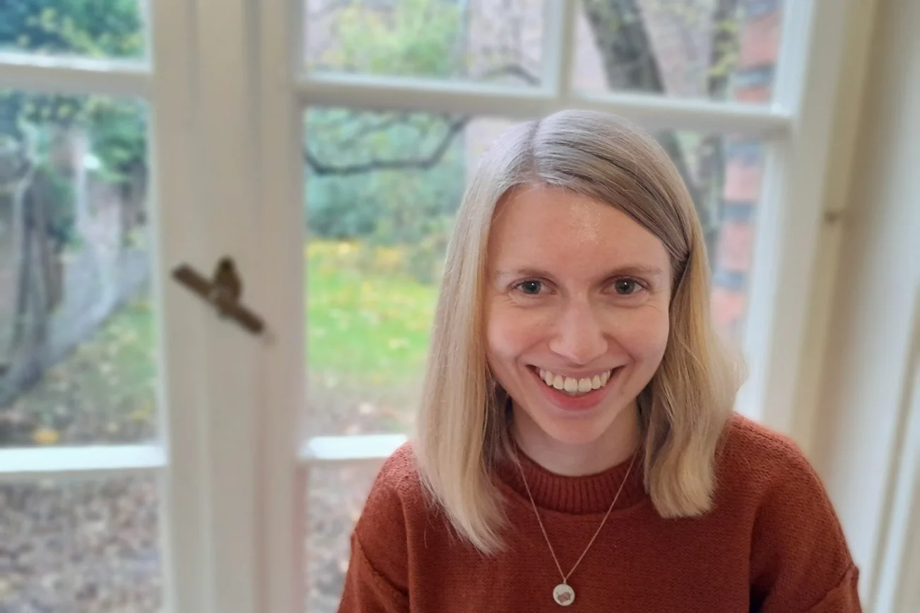 Eine junge Frau mit blonden Haaren lacht in die Kamera