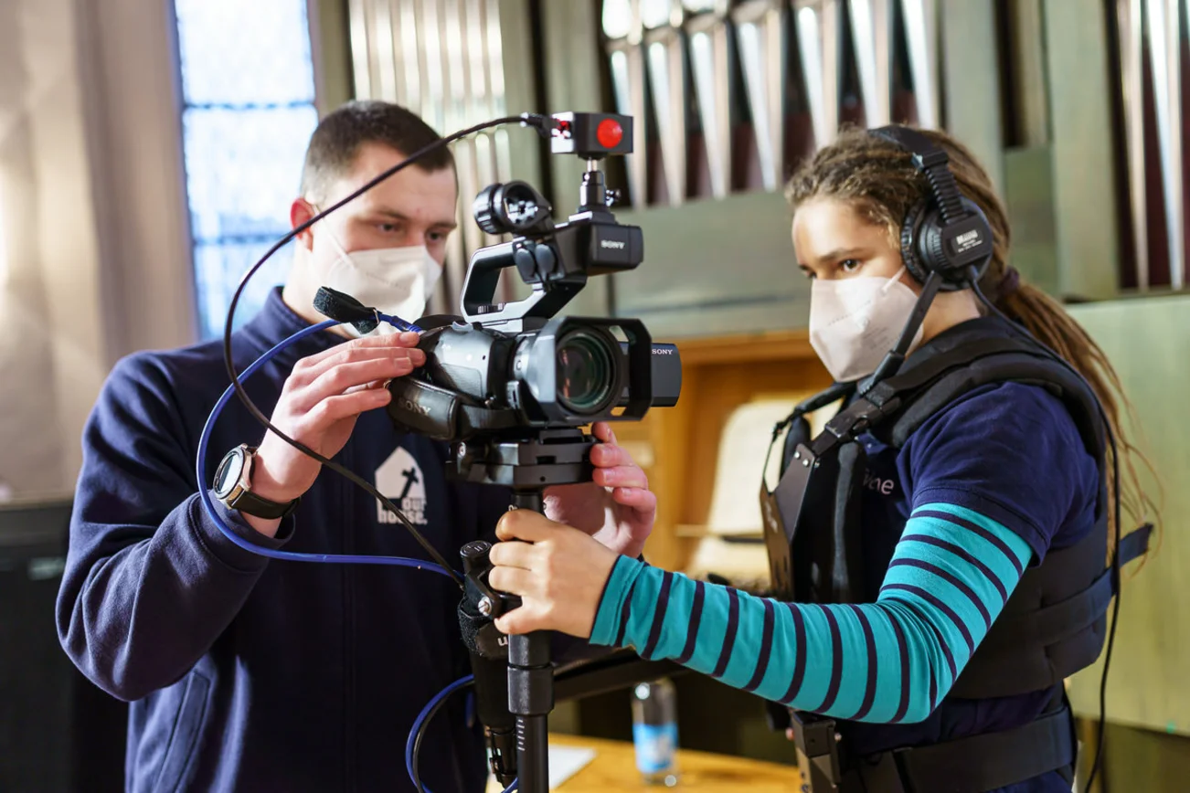 Zwei Personen schauen sich eine mobile Kamera an. 
