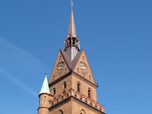 Die Turmspitze der Herz-Jesu-Kirche ragt in den blauen Himmel