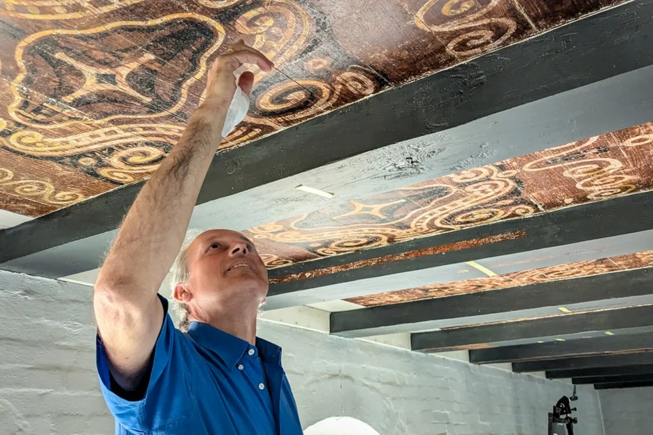 Ein Mann zeigt Deckenmalereien