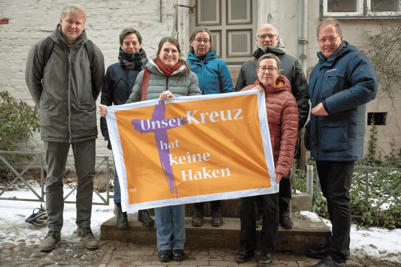 Personen halten Banner und schauen in die Kamera