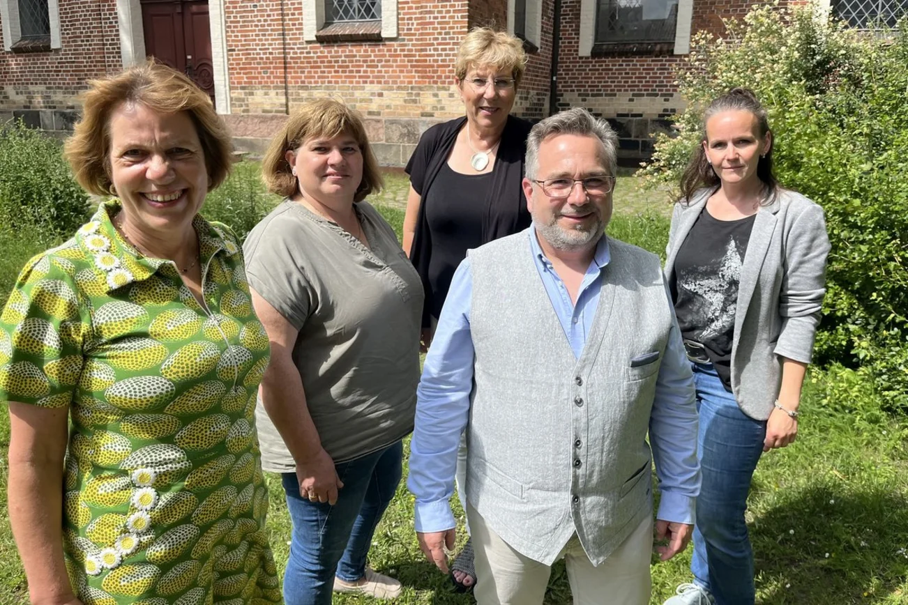 Ein Mann und vier Frauen stehen in einem Garten