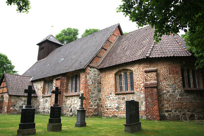 Drei Steinkreuze stehen vor der St.-Laurentius-Kirche auf grünem Rasen - Copyright: Ev.-Luth. Kirchenkreis Lübeck-Lauenburg