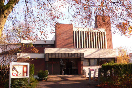 Der Eingangsbereich der Friedenskirche ist zu sehen. Links im Vordergrund steht ein Schaukasten. 