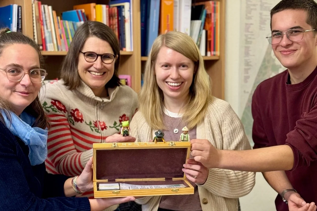 Vier Personen halten einen geöffneten Schachkoffer in den Händen.