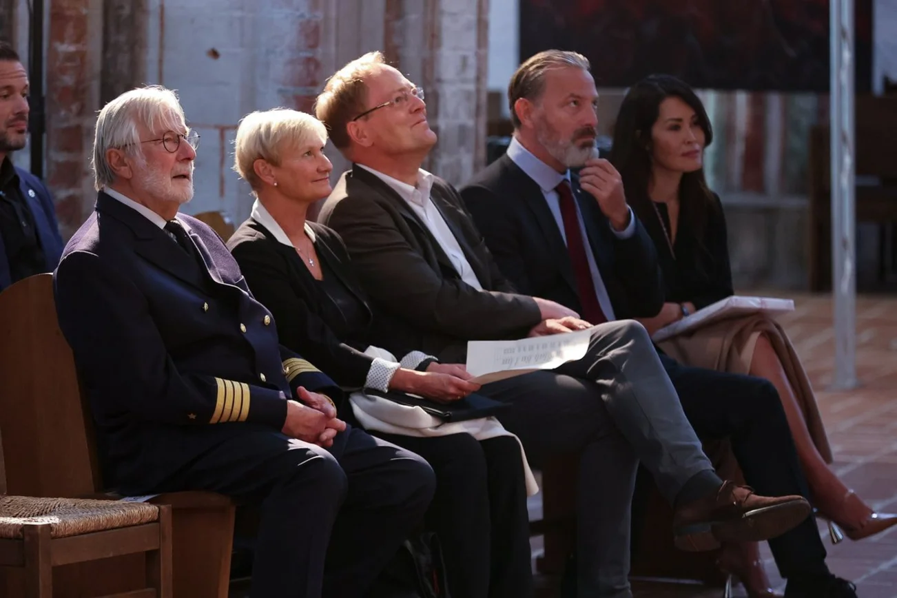Mehrere Personen sitzen auf einer Kirchenbank