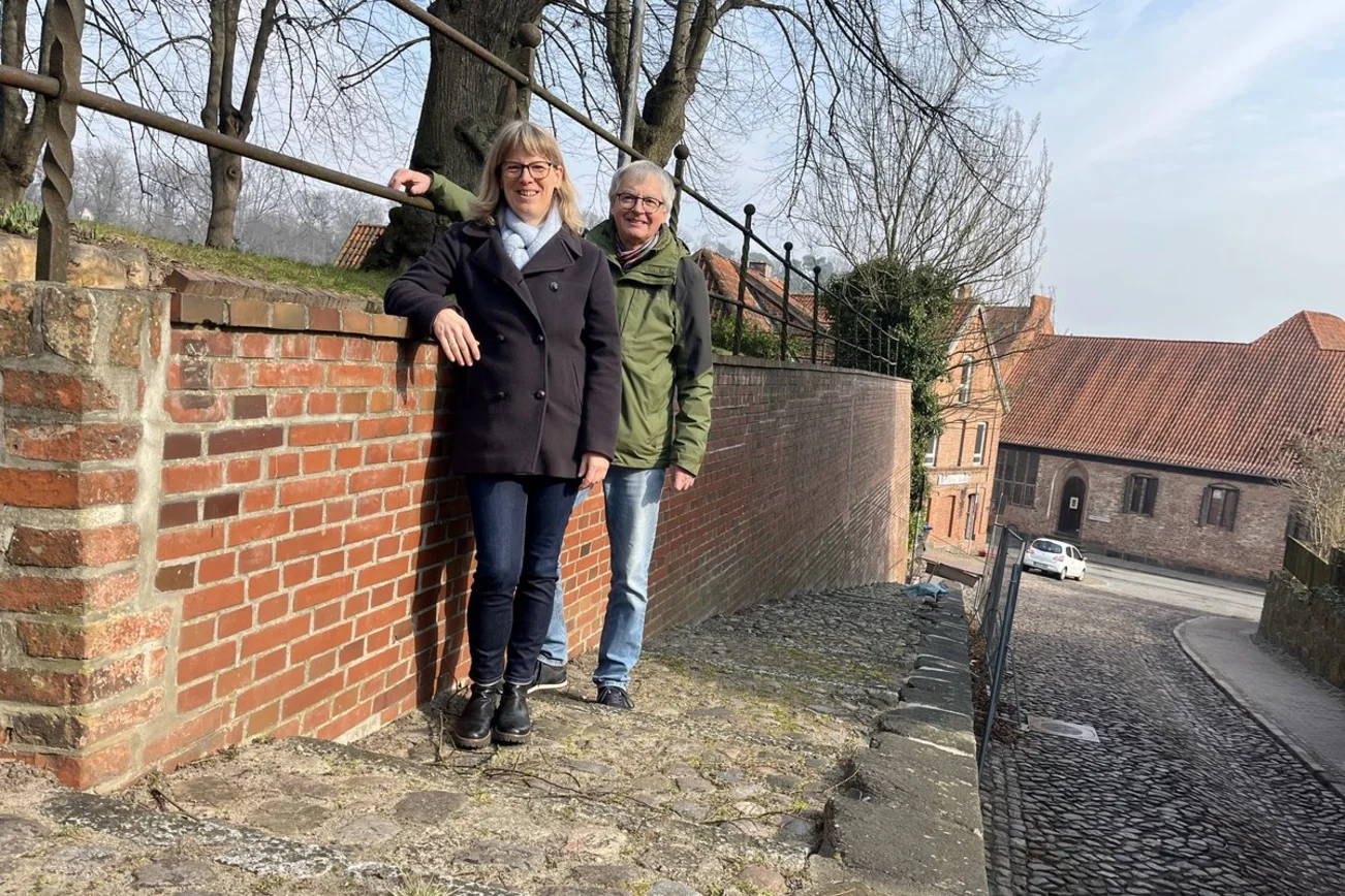 Eine Frau und ein Mann stehen auf einer Treppe und lehnen an einer Mauer.