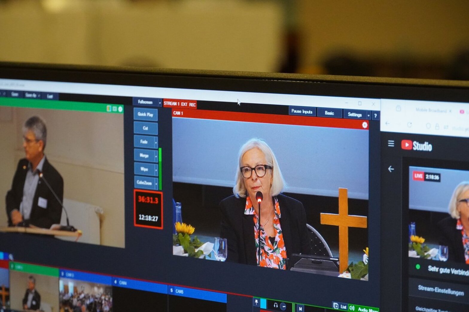Ein Bildschirm der eine Frau zeigt, die an einem Mikrofon sitzt.