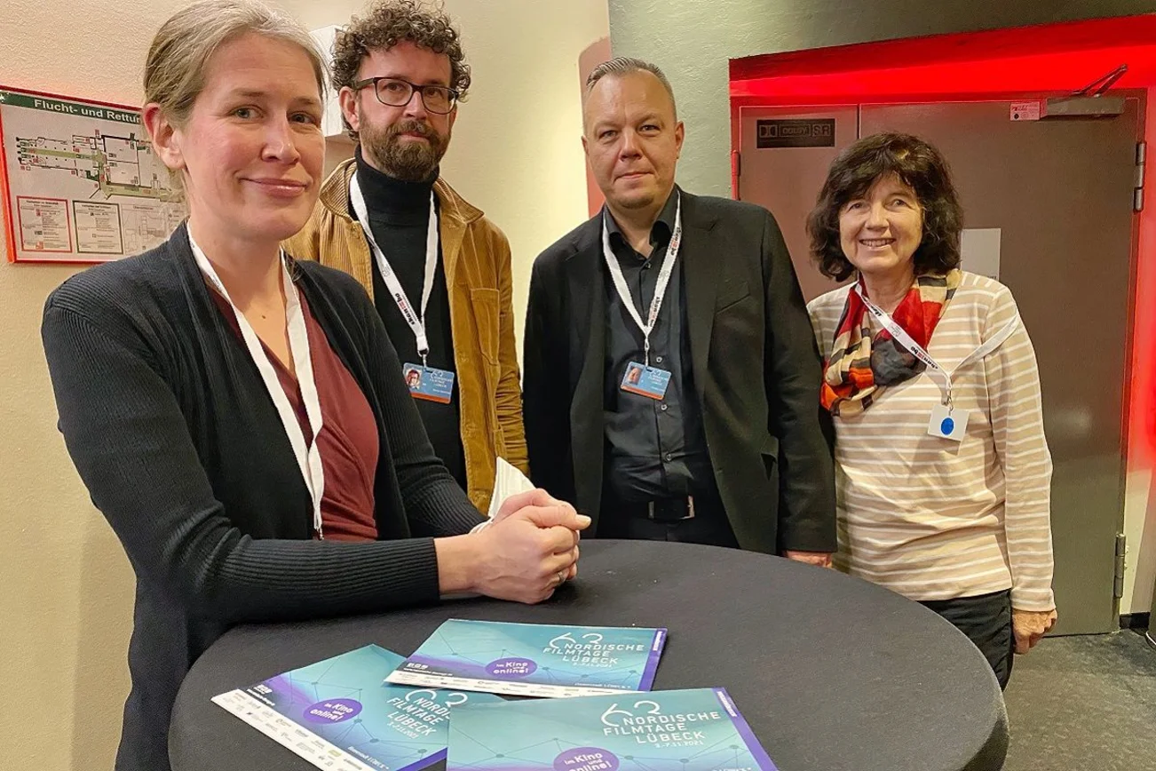 Gruppenbild, vier Personen lächeln in die Kamera.