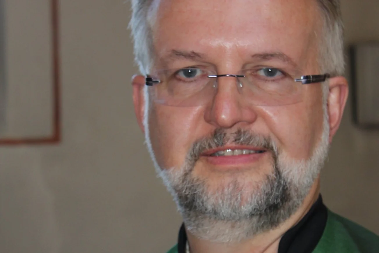 Ein Pastor blickt in die Kamera. 