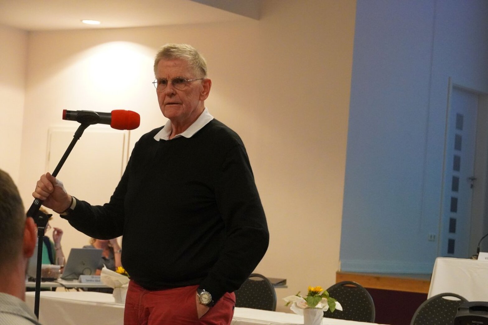 Ein Mann mit grauen Haaren steht an einem Mikrofon