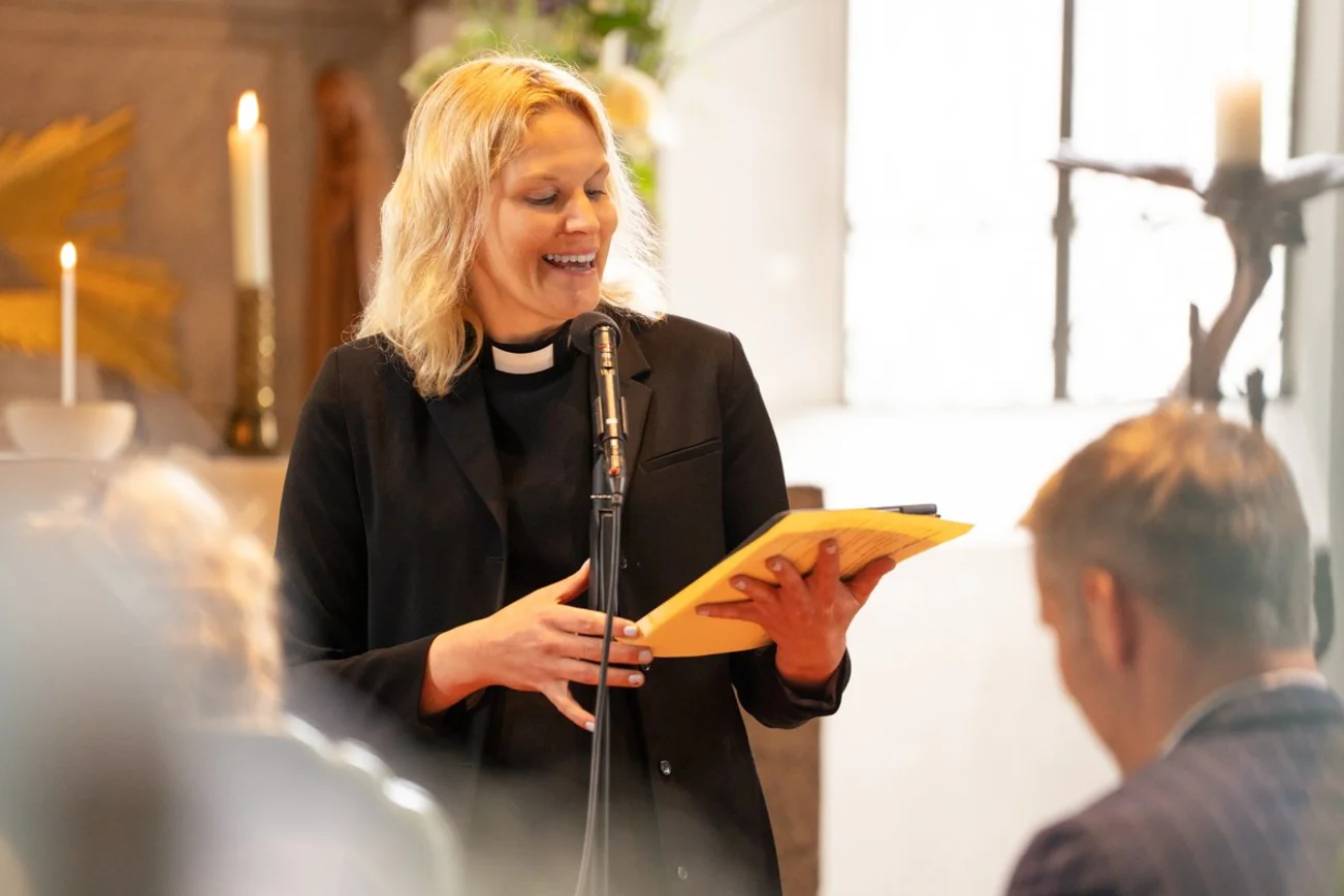 Eine Pastorin liest lächelnd von einem Blatt ab. 