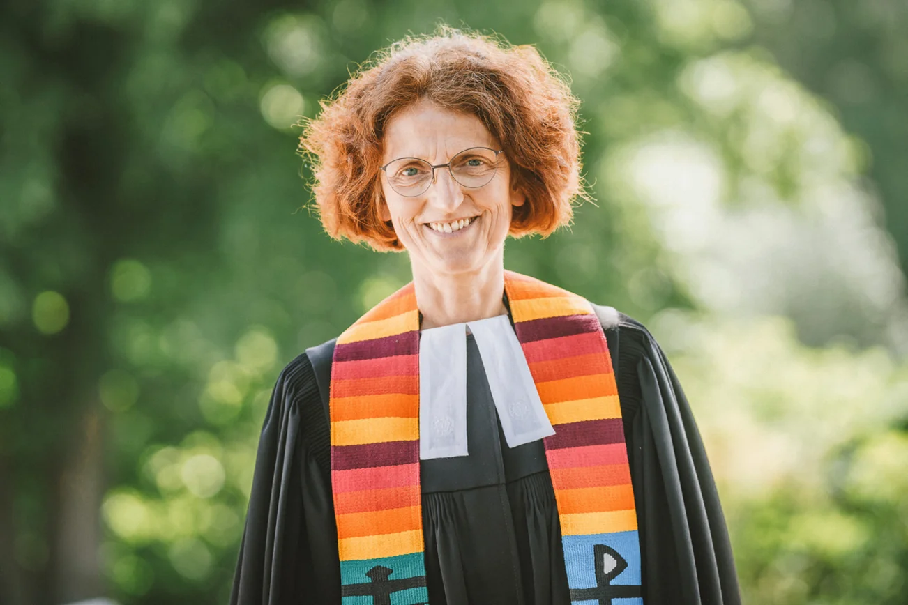 Eine Frau im Talar lächelt in die Kamera.