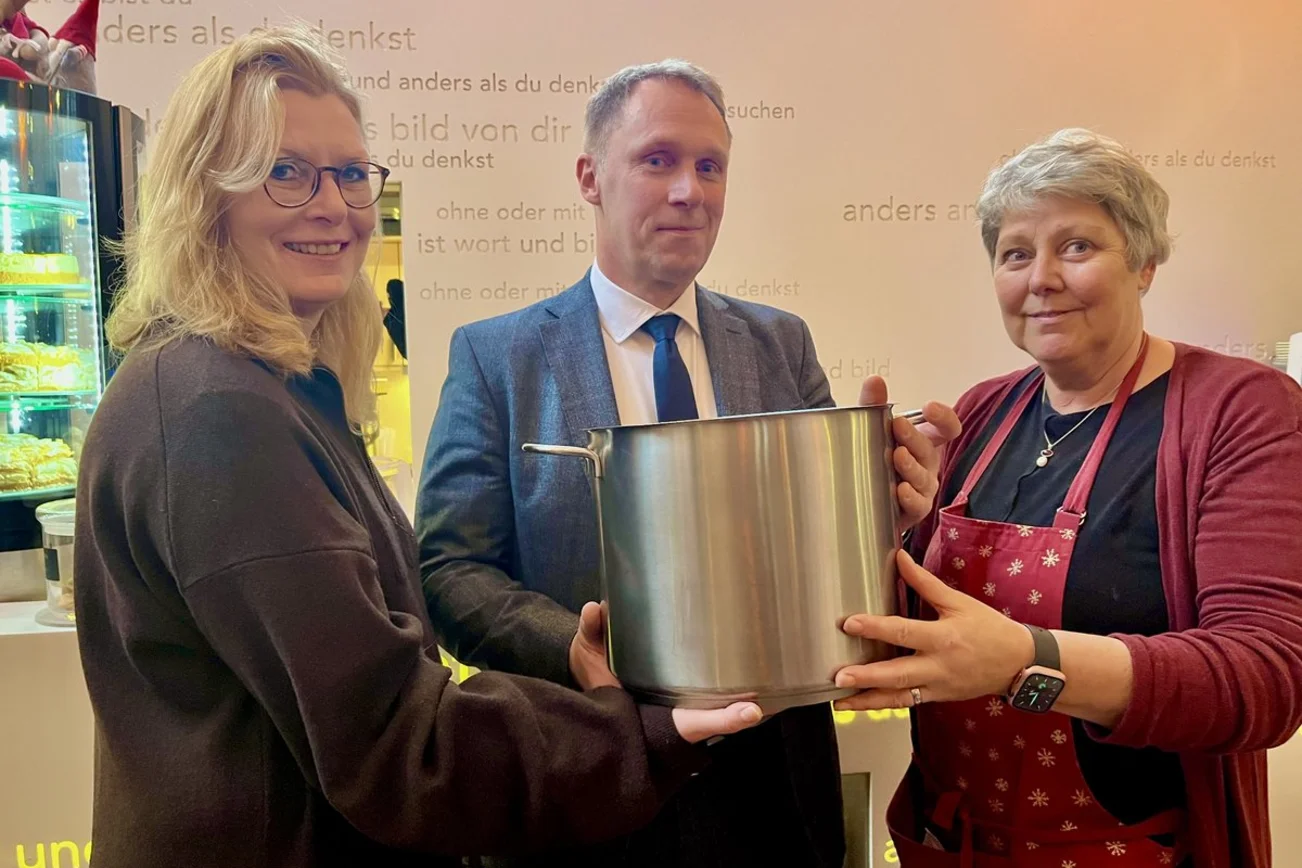 Drei menschen halten einen Kochtopf