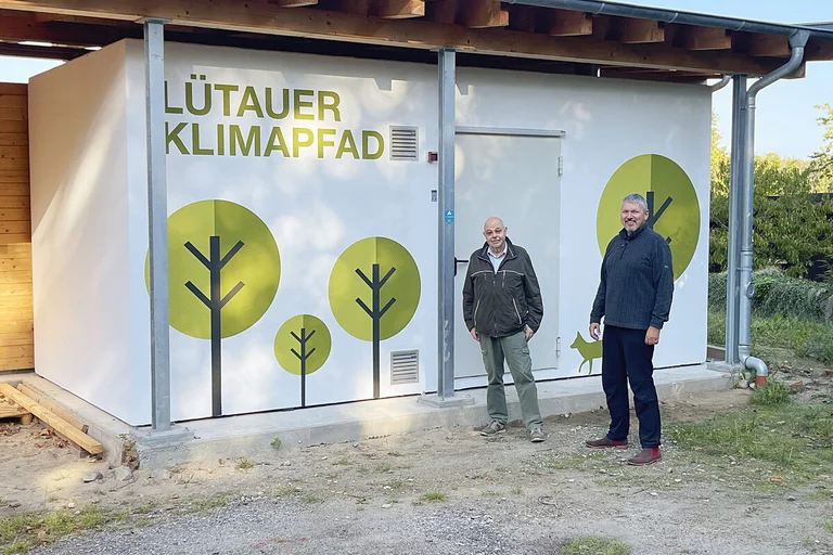 Zwei Männer stehen vor einem Gebäude. 