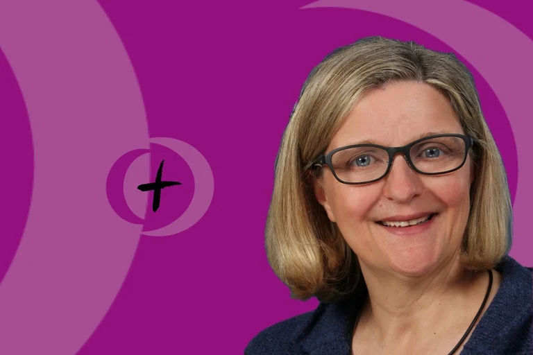 Eine Frau blickt in die Kamera und lächelt.