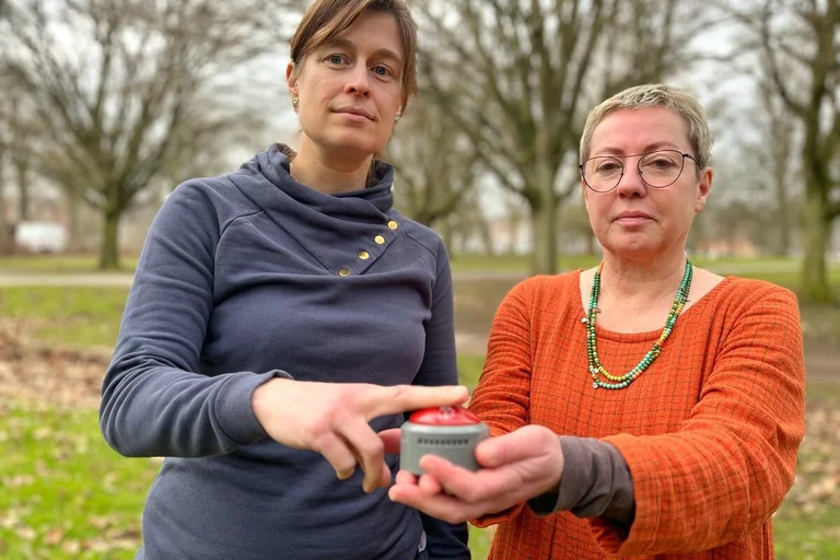 Sei Frauen stehen mit einem Alarmbutton in einem Park