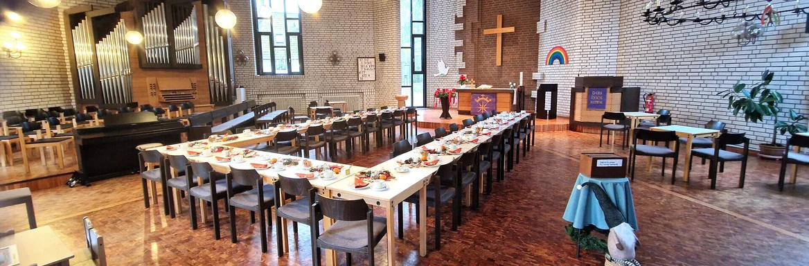 Tische und Stühle in U-Form aufgebaut mit Kaffeegedeck in einer Kirche