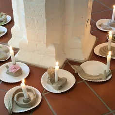 Kerzen auf Tellern stehen um eine Säule