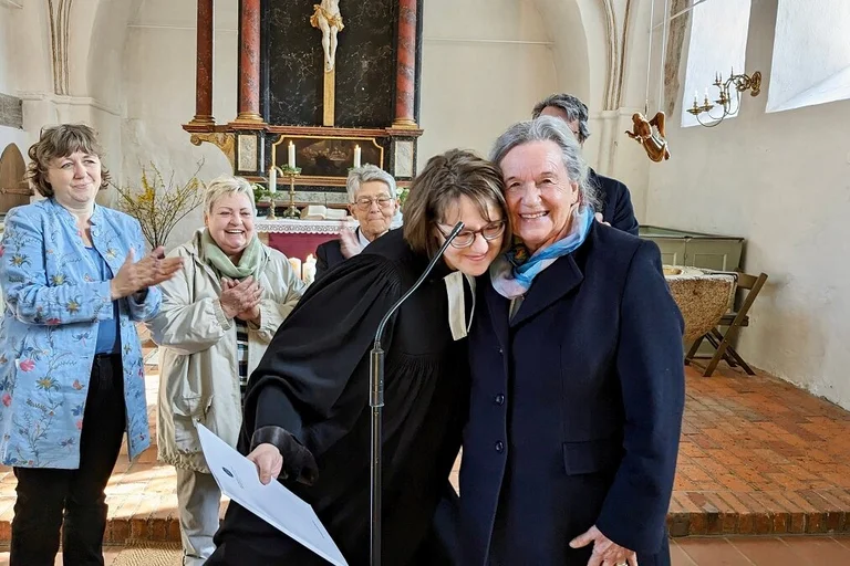 Zwei Personen vorn und mehrere Personen dahinter in einer Kirche