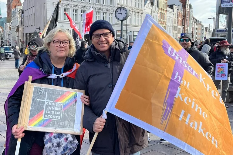Mann mit Mütze und Brille hält Flagge.