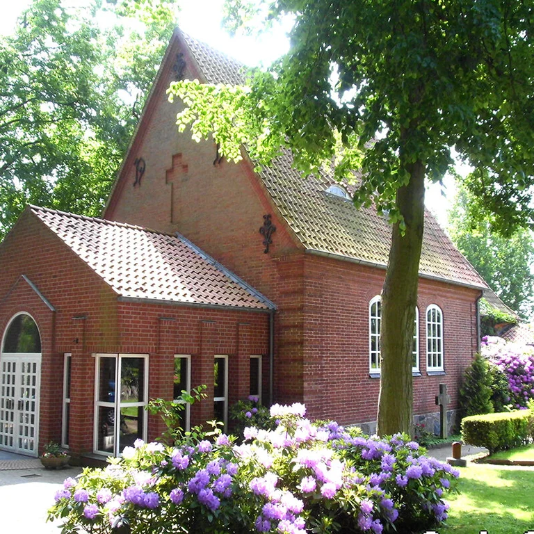 Friedhofskapelle St.-Lorenz Travemünde mit blühenden lila Rhododendron-Pflanzen