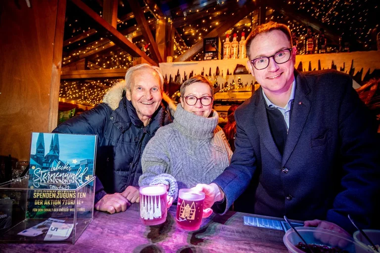 Drei Menschen lächeln in die Kamera