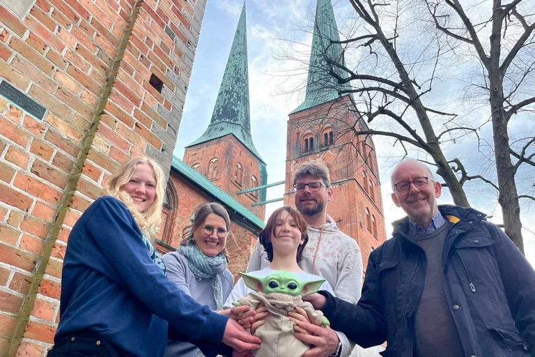 Fünf Menschen stehen zusammen vor den Lübecker Dom-Türmen.