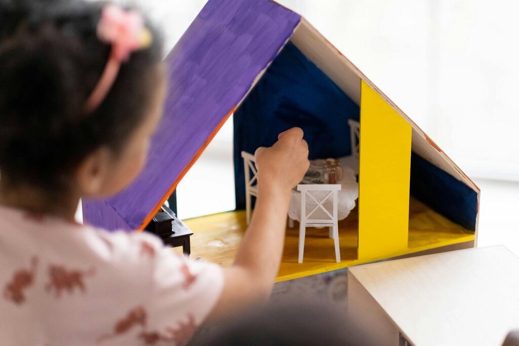 Ein Kind spielt mit einem kleinen bunten Puppenhaus