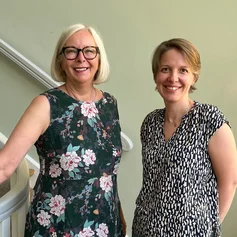 Zwei Frauen stehen an einem Treppengeländer.