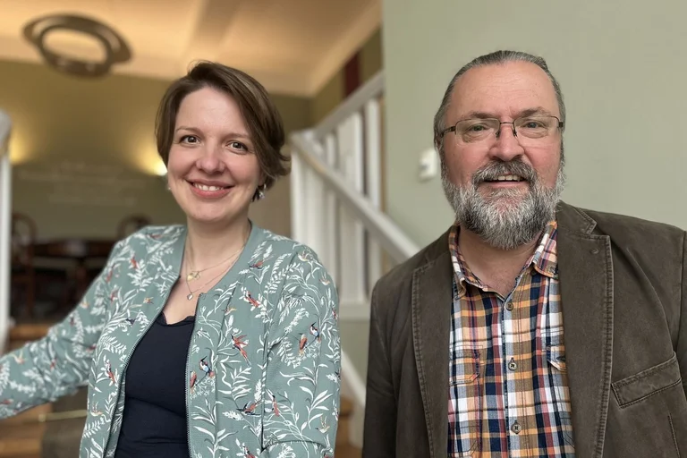 Eine Frau und ein Mann stehen auf einer Treppe in einem Haus.