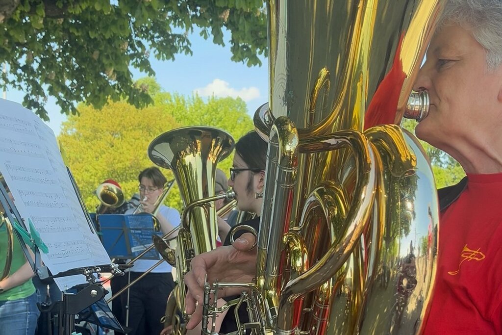Mehrere Personen spielen im Freien in einem Posaunenchor