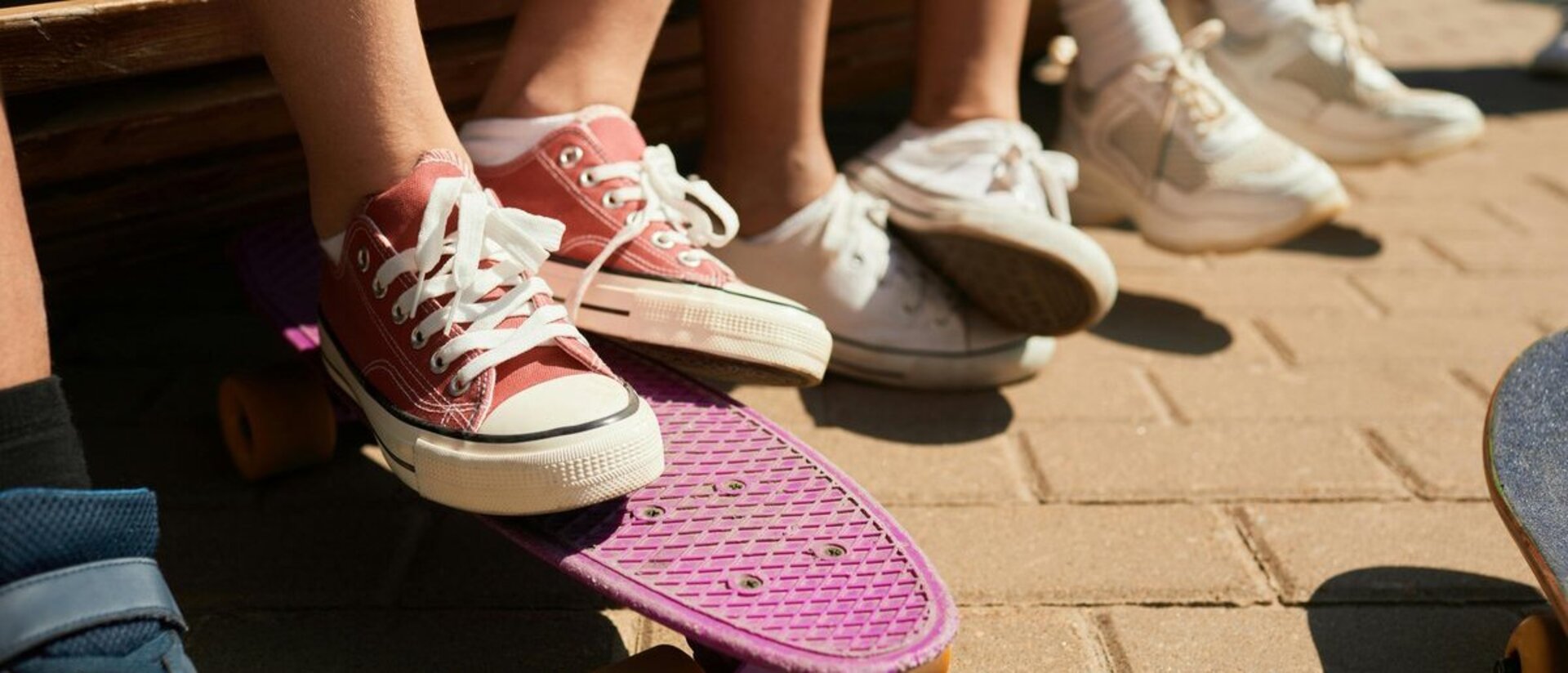 Mehre Füße in Sneakers, davon ein paar auf einem Skateboard