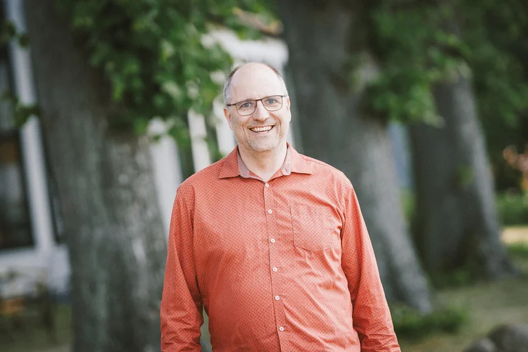 Ein Mann lächelt in die Kamera.