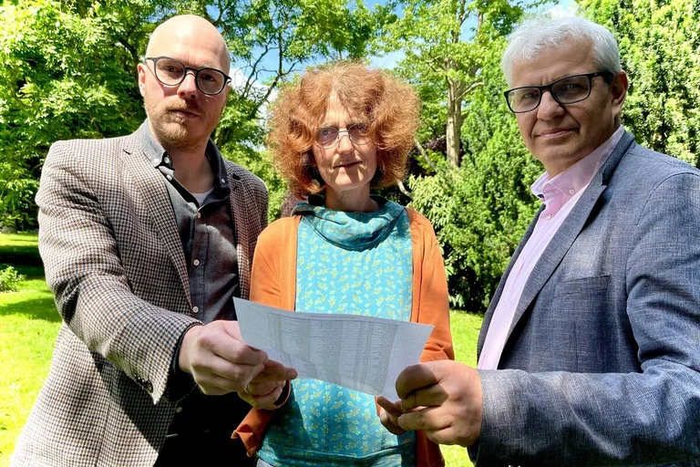 Drei Menschen halten einen Brief in den Händen