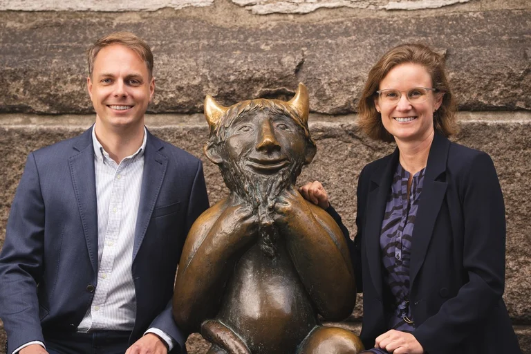 Zwei Menschen sitzen an einer Skulptur